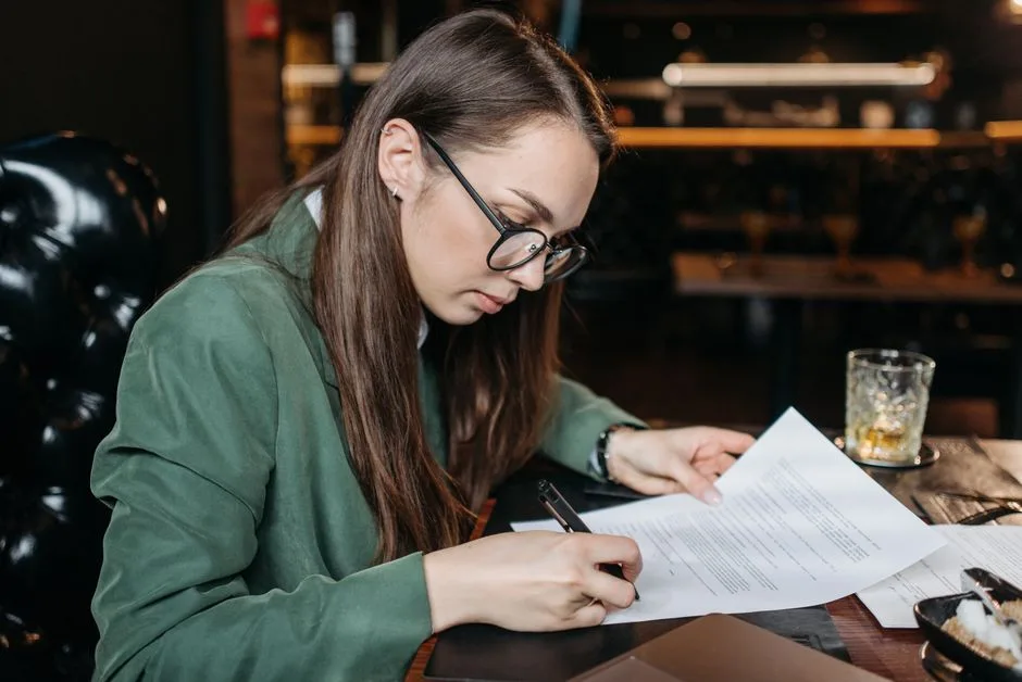 Un dirigeant en chemise relit un contrat de responsabilité civile dans son bureau, documents ouverts.